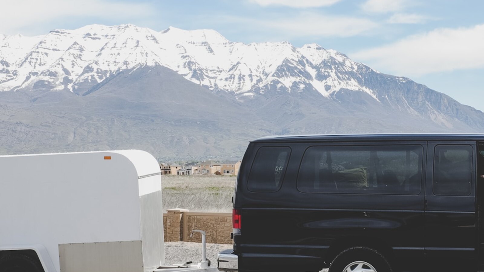 Schwarzer Tour-Van mit Anhänger vor einem Bergpanorama